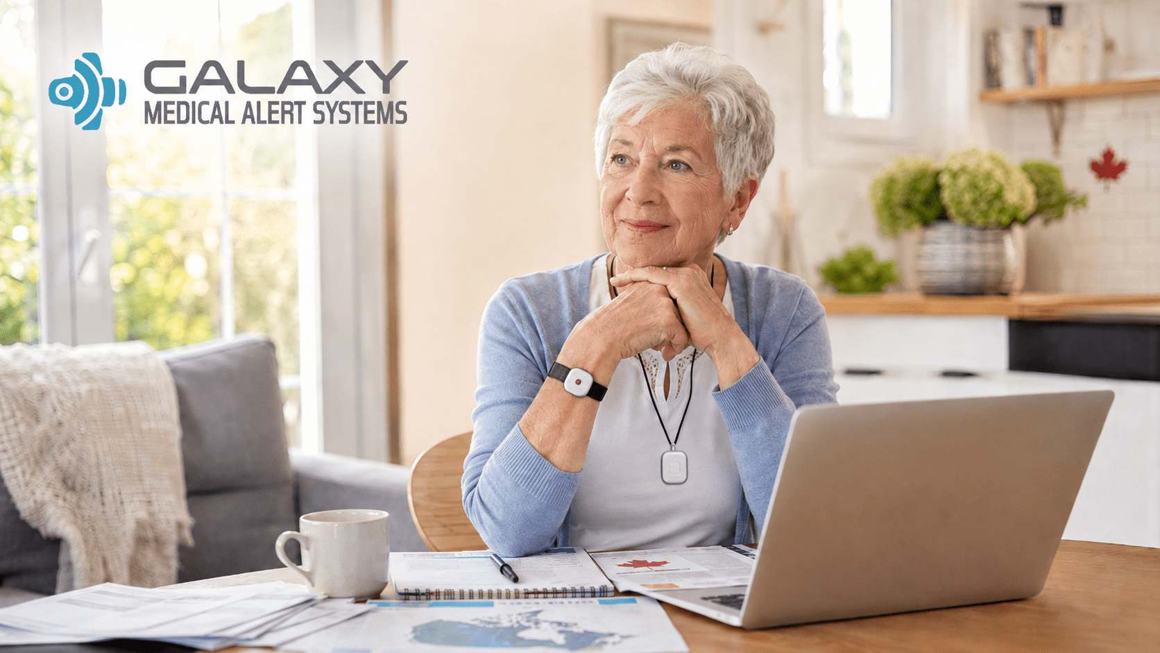 Senior in Canada wearing a Galaxy medical alert system pendant and wrist button, reviewing medical alert system coverage options on a laptop